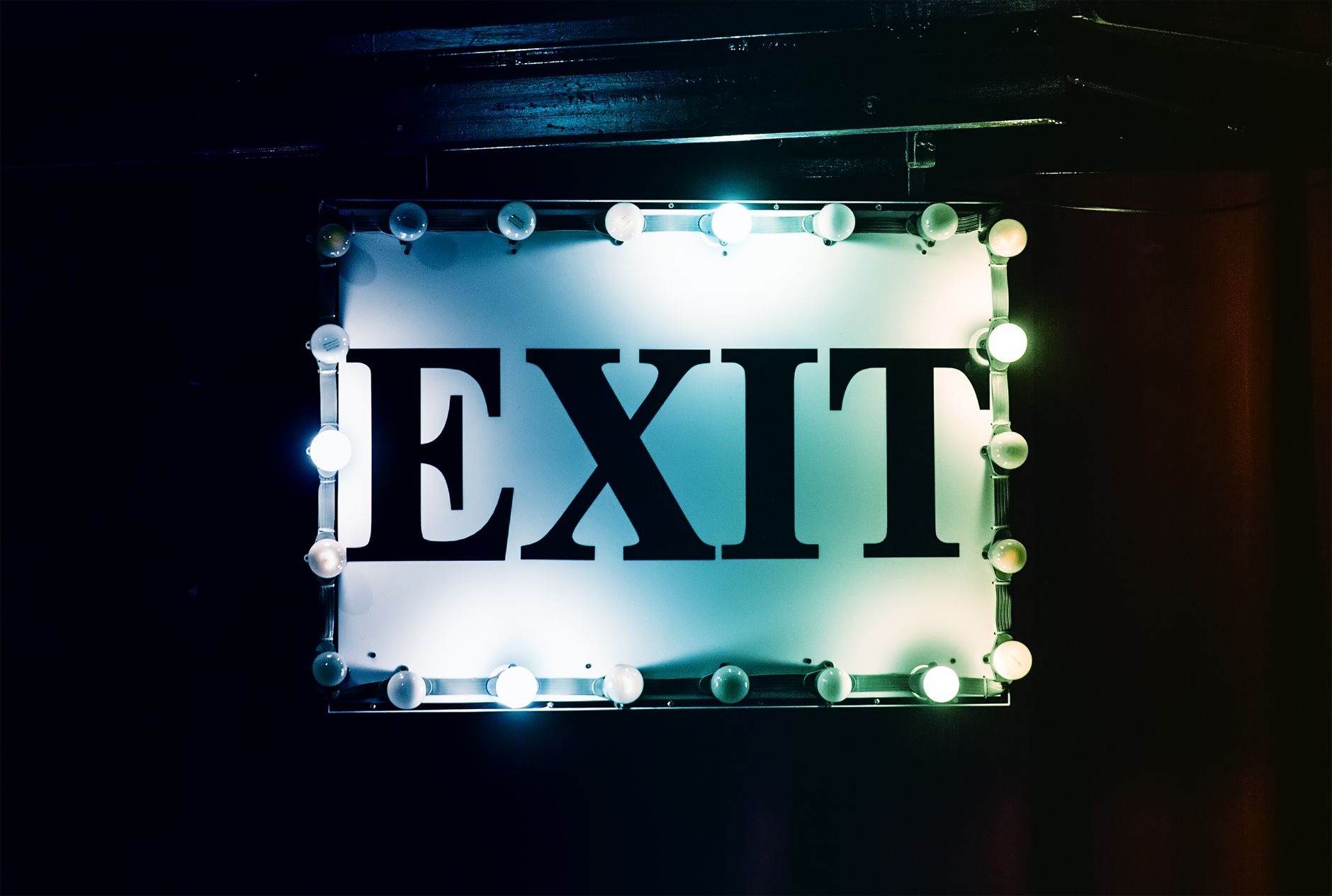 Brightly lit exit sign against a dark background, evoking a vintage aesthetic.